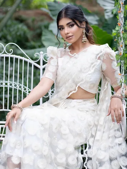 A seated portrait in the white saree, conveying a sense of modern grace.