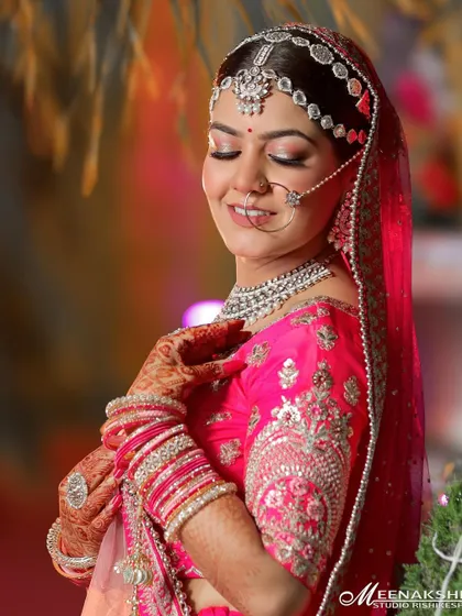A radiant portrait of a bride in a vibrant pink lehenga. Her happy expression and the beautiful silver embroidery of her outfit are the highlights of this shot.