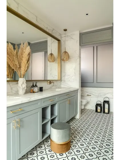 This bathroom combines classic and modern elements, with soft grey cabinetry, patterned floor tiles, and elegant gold accents for a touch of luxury.
