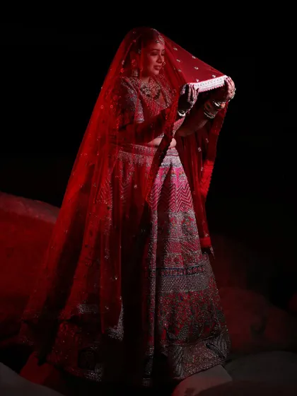 A dramatic portrait of the bride under her red veil, creating a striking and timeless image.