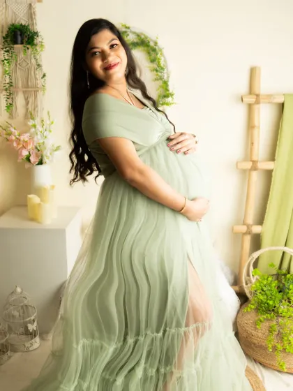 A beautiful side-profile shot in a sage green gown. The pose is elegant and perfectly showcases the pregnancy silhouette.