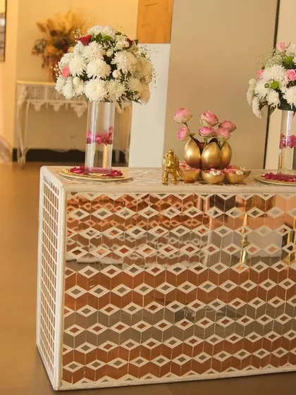 A stylish mirror console table at the entrance, decorated with tall floral arrangements and other decorative items. This piece adds a touch of modern glamour to the wedding decor.