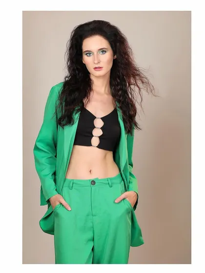 A front-facing shot of the green pantsuit look. The model's hands in her pockets give it a relaxed yet confident vibe.