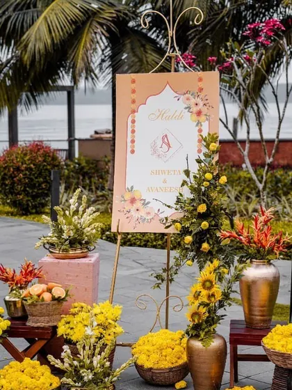 A welcome sign for a Haldi ceremony, set against a beautiful waterside backdrop.