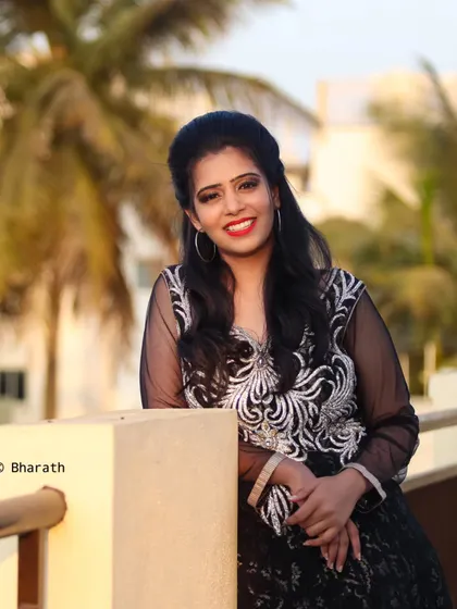 A relaxed pose on a balcony during sunset. The palm trees in the background add to the warm, evening atmosphere.