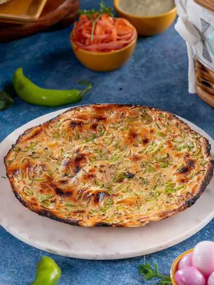 Freshly baked naan with a generous spread of green chilies, presented on a marble platter. This shot highlights the texture and savory appeal of the bread, a staple accompaniment to many Indian dishes.