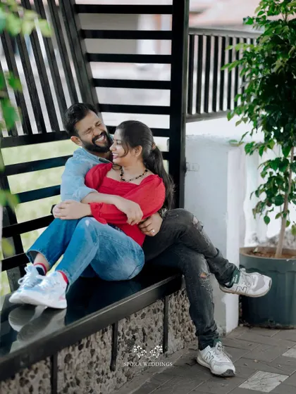 The couple sharing a laugh while seated together on a modern black bench.