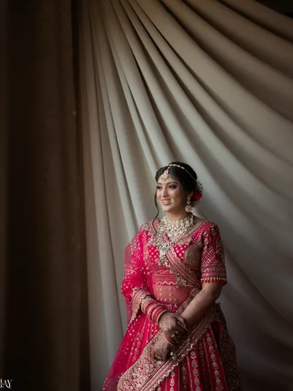 A classic bridal portrait by a window, with soft light illuminating her happy expression.