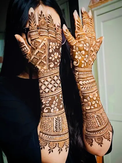 A happy client showing off her full-coverage back-of-hand mehandi, which features a beautiful mix of floral and jaali patterns.