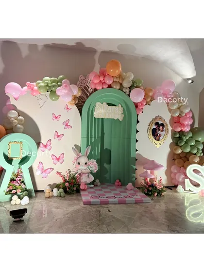 An enchanting 'Alice in Wonderland' inspired high tea party setup. The backdrop features a keyhole cutout, a checkered floor, and whimsical characters, creating a magical wonderland for guests.