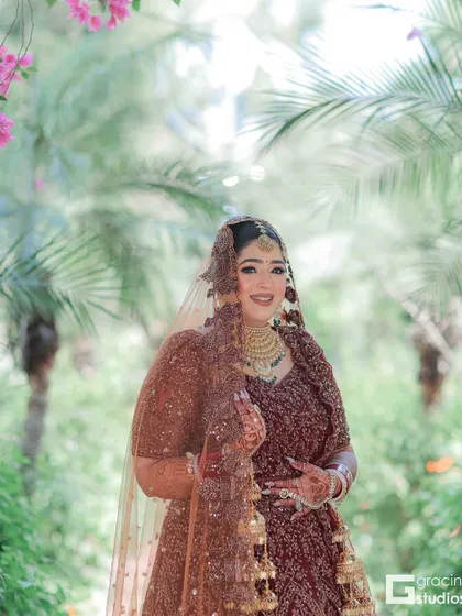 A full-length shot of the bride in a beautiful outdoor setting. The makeup is designed to look natural and radiant.