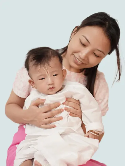 A mother holds her baby close, her gentle expression full of love. A simple, clean portrait that highlights the tender bond between them.