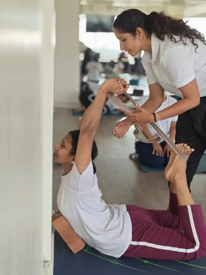 Using a wall and blocks for support in Dhanurasana allows for a deeper, more restorative backbend. Our TTC students learn these therapeutic applications of asanas.