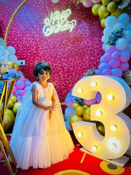 A princess moment for Cherry at her 3rd birthday. She poses next to the giant light-up number '3' we provided, with a colorful balloon arch and neon sign creating a festive backdrop.