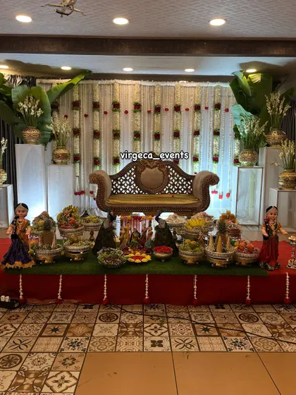 Here is a full view of a traditional Seemantha decoration. The stage is set with a backdrop of jasmine flower strings, banana leaves, and a beautiful arrangement of seer plates with dolls and peacock figures.