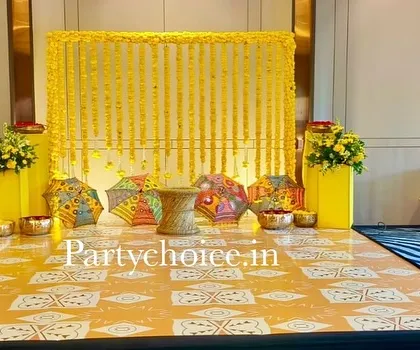 We designed this indoor Haldi setup with a dominant yellow theme. The backdrop is a curtain of marigold strings, complemented by colorful Rajasthani umbrellas and a custom-printed floor mat for a cohesive and cheerful look.