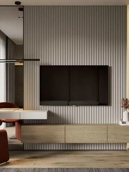 This design merges a workspace and entertainment unit into one seamless feature wall. The floating desk and TV console are unified by a light wood finish and a vertical fluted panel, making it a perfect solution for modern, multi-use living areas.