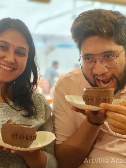A couple playfully shows off the matching cups they created during a date workshop. You get to take home not just your art, but also a fun memory.