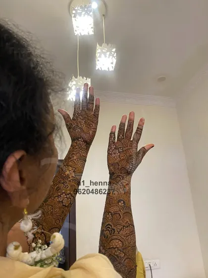 A bride showing off her full-sleeve henna. The design is rich and detailed, ensuring it looks incredible in wedding photos.