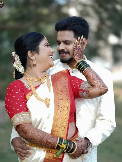 A classic wedding portrait where the bride lovingly touches the groom's face. The image highlights the bride's intricate henna and traditional green bangles, key details of her bridal look.