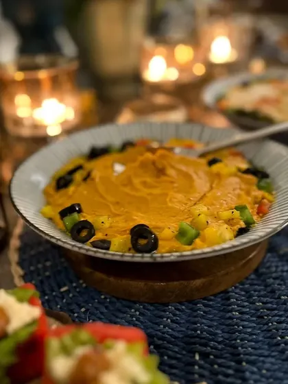 A bowl of roasted red pepper hummus, adding a vibrant color and smoky flavor to our Mediterranean offerings. Perfect for dipping with fresh bread or vegetable sticks.