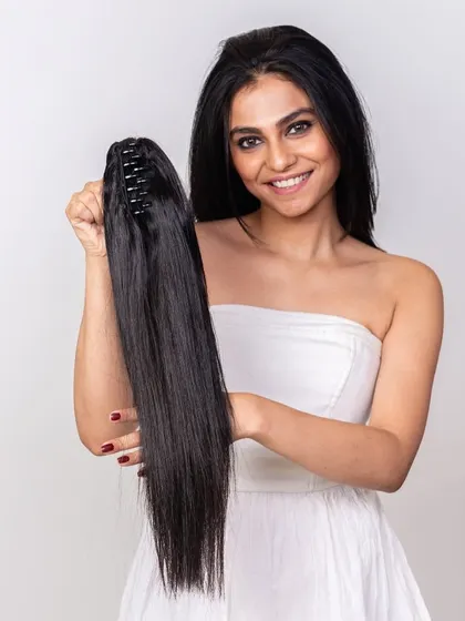 A clutch ponytail is one of the simplest ways to transform your look. Here, the model is holding the easy-to-use clip-in piece, ready to create a stunning hairstyle.