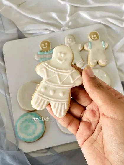 A hand-iced gingerbread man cookie, part of a Christmas-themed cookie set. Custom cookies are a great way to celebrate any holiday.