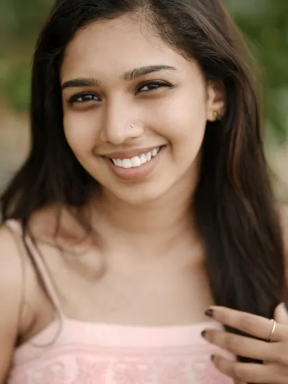 A simple, beautiful, and natural portrait. The close-up shot and her genuine smile create an honest and engaging image that truly captures her personality without any distractions.