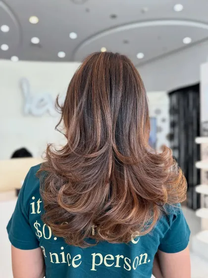 A view from the back of this glossy brown color. The layers are perfectly defined by the subtle highlights and bouncy curls.