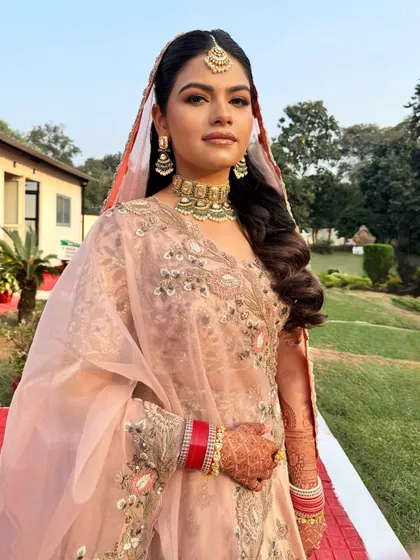 This bride is shining brighter than the sun on her wedding day. I created a radiant, minimal makeup look with open, wavy hair to match her pastel lehenga for a modern bridal style.