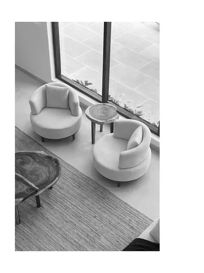 This black and white shot emphasizes the form and texture of the furniture and the natural light from the large window. The minimalist composition highlights the clean lines and simple elegance of the design.