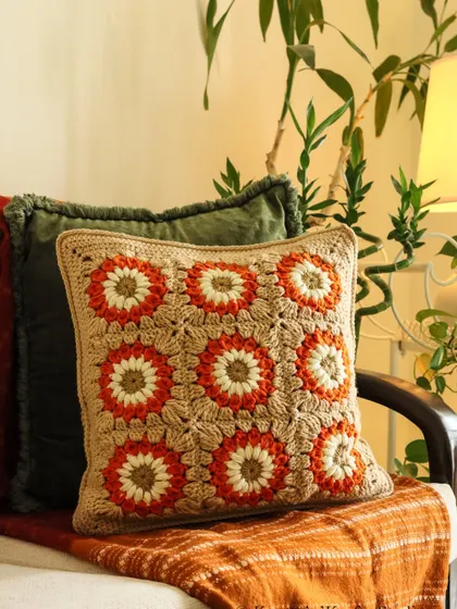 A close-up of the Sundowner cushion, showing the intricate stitch work and the beautiful blend of orange, white, and beige.