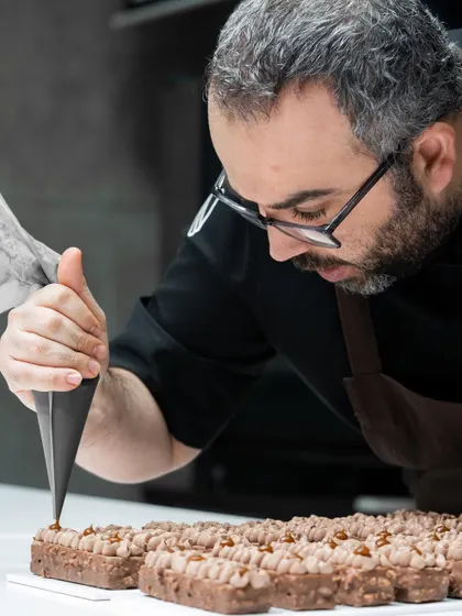 Chef Bourgi piping a detailed pattern on a travel cake.