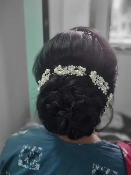 A classic and elegant bridal bun. This intricate updo is decorated with a beautiful crystal hair accessory, perfect for a reception or engagement party.