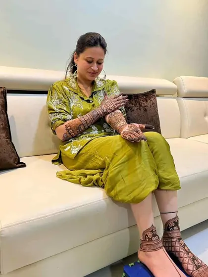 A client admiring her mehndi, which includes designs on her hands and feet.