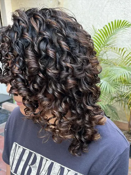 A side view of the bleach-free highlights on her curly hair.