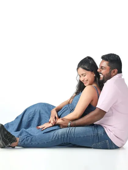 A fun and playful shot of a couple sharing a laugh. This candid moment on a simple white background shows the happy and lighthearted side of their journey to becoming parents.