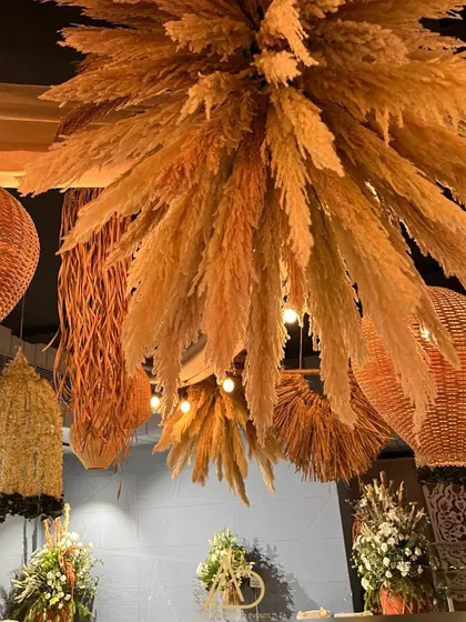 A stunning ceiling installation made entirely of pampas grass, creating a massive, cloud-like chandelier that is both rustic and luxurious.