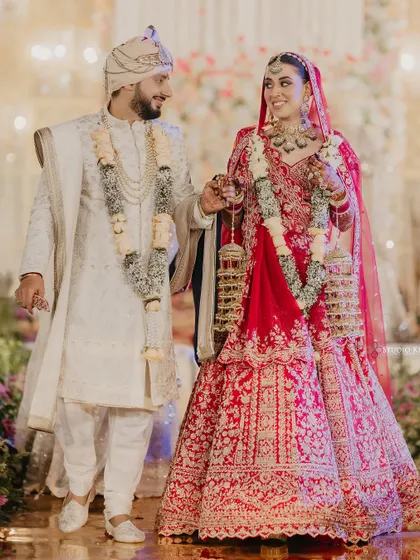 The couple walking hand-in-hand, smiling at each other, capturing a candid moment of happiness.