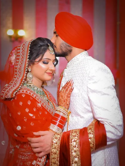 An intimate moment after the main ceremony, with the groom kissing the bride's forehead.