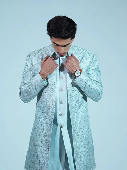 A close-up of the light blue Indo-western sherwani, showing the detailed embroidery and the buttons.