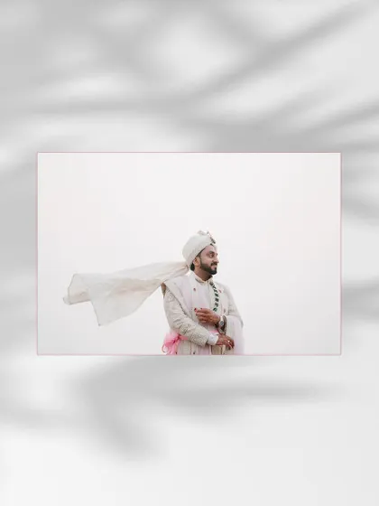 An artistic portrait of the groom with his stole blowing in the wind, creating a dramatic and stylish shot against a minimal background.