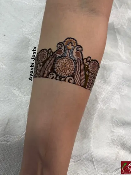 A close-up of an arm band for an engagement design, featuring parrots and floral motifs.