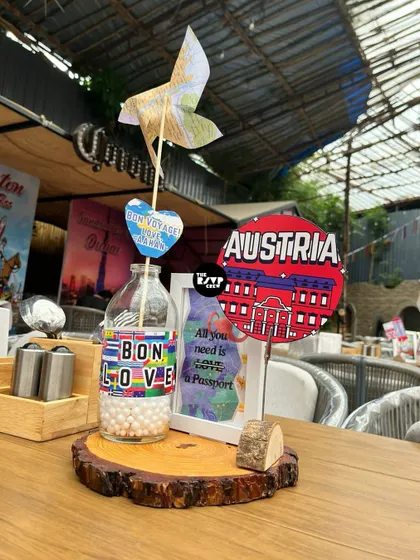 A creative table centerpiece for the travel party, featuring a bottle filled with 'Bon Voyage' candies and a sign for Austria.