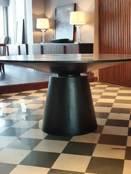 Here is another view of one of our favorite dining tables, showcasing its solid, conical base and expansive top. The dark finish gives it a commanding presence, perfect for modern and classic interiors alike.