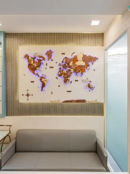 This waiting area features a stunning backlit wooden world map, serving as both art and a brand statement. The comfortable sofa and minimalist side tables create a welcoming space for visitors.