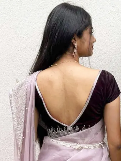 A client wearing a deep V-neck velvet blouse with delicate crystal work along the border.