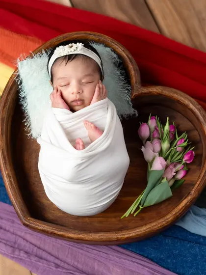 Nestled in a heart-shaped wooden bowl, this sleeping baby looks so peaceful. I added a small bouquet of tulips to bring a touch of color and softness to this newborn portrait.