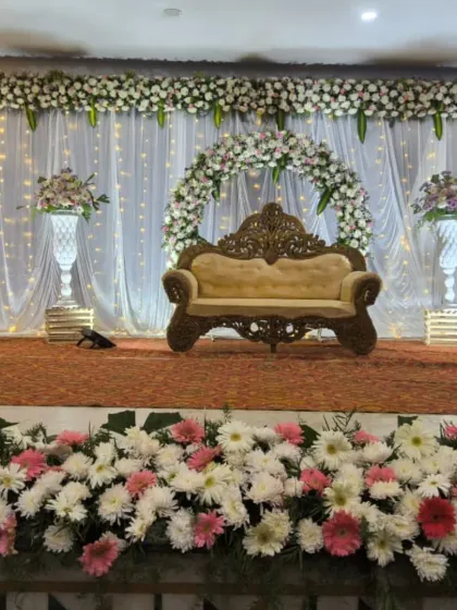 A classic white-themed reception stage with a floral arch, crystal vases, and a traditional sofa, offering a timeless and elegant look.