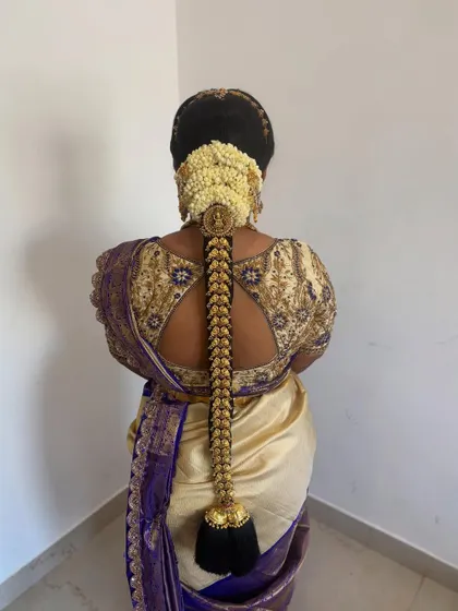 A full length view of a classic bridal braid with gold 'Jadai' and a jasmine 'Gajra'. This hairstyle is a perfect match for a traditional Kanjeevaram saree.